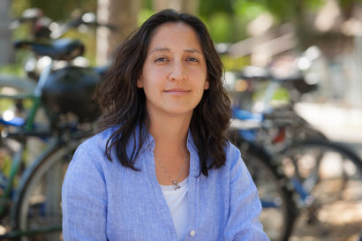 Tina Trujillo, a professor at the Graduate School of Education, looks into the camera. She is sitting in front of a row of bicycles.