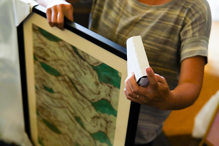 a person holds a framed artwork