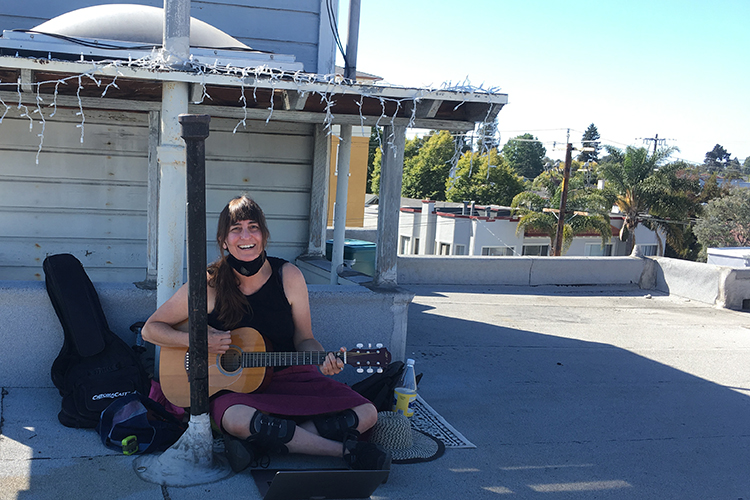 a person sits on the ground outside playing guitar