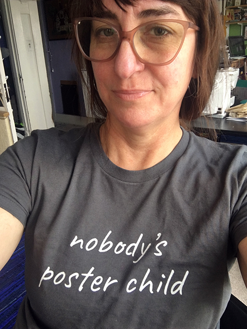 a person takes a selfie wearing a shirt that says "Nobody's poster child."