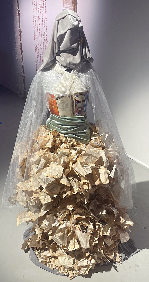a sculpture off a dress made from book pages and a scarf for a head
