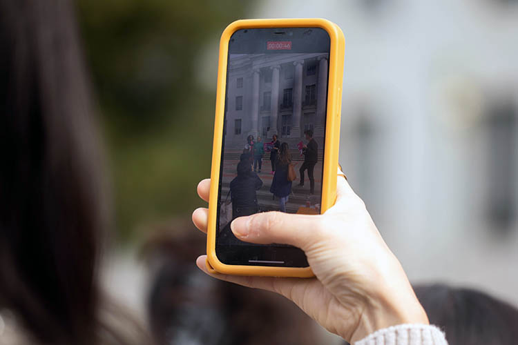 a photo of a person recording video on aniphone iwth a yellow case