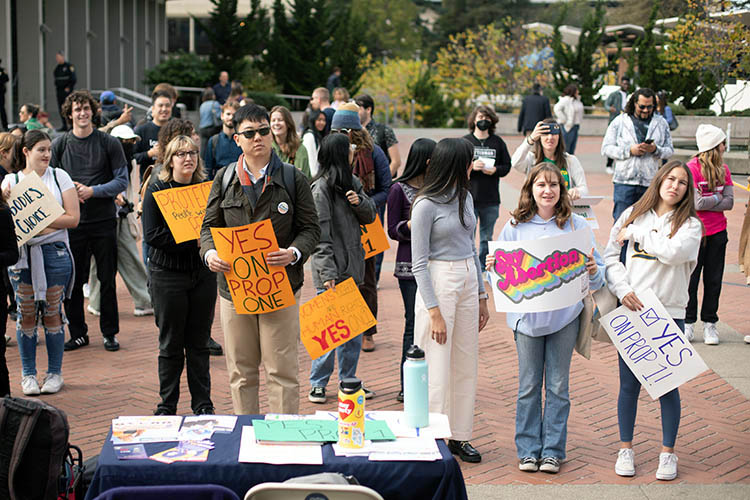 a crowd gathers on sproul plaza holding signs in favor of prop 1