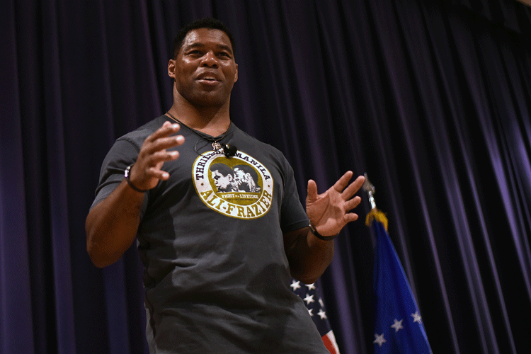 Herschel Walker, Georgia's Republican candidate for governor, wearing a black shirt and gesturing on a stageU