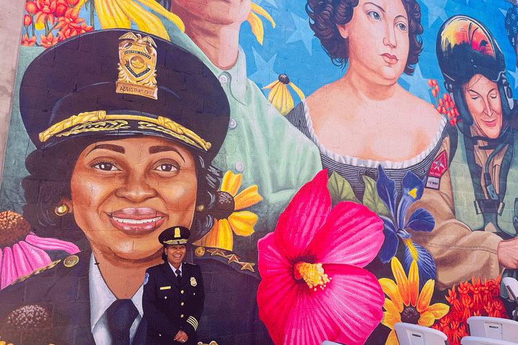 Yogananda Pittman looks tiny as she stands next to a mural that features her likeness in her hometown of Cambridge, Maryland.