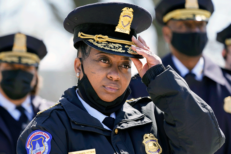 Yogananda Pittman, while interim chief of the U.S. Capitol Police, adjusts her cap as she stands outdoors with other officers