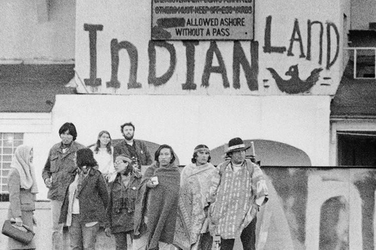 black and white photo of nine people standing in front of a wall in 1969 that reads 