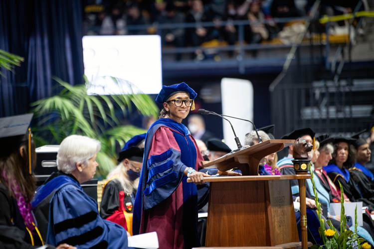 a woman stands and speaks at a podium