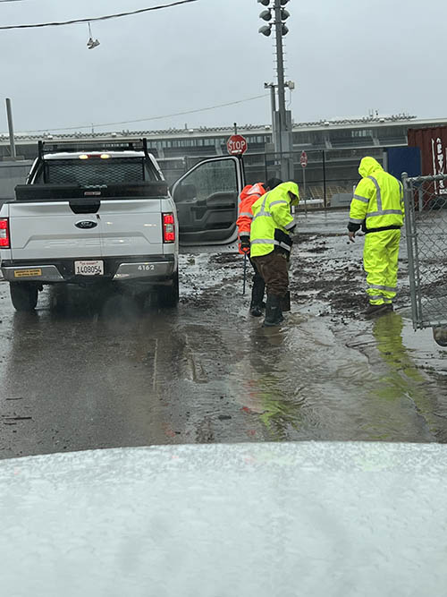 three men in safety gear clear debris in the rain