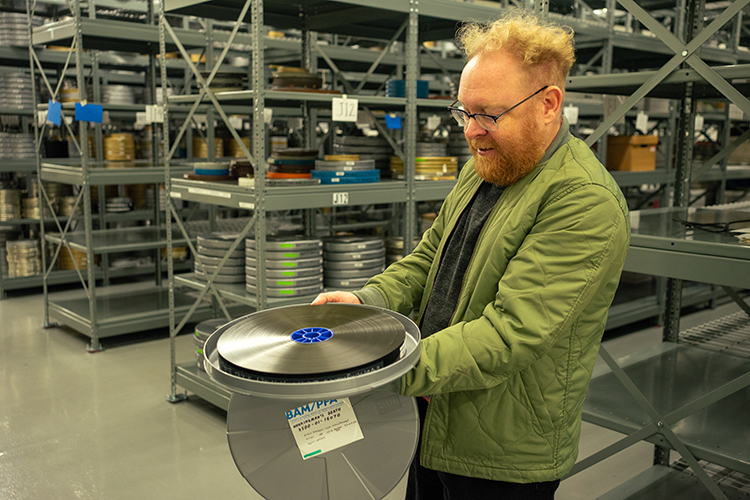 Jason Sanders, BAMPFA's film research specialist, examines a 35mm film stored in one of thousands of metal film cans at the archive's vault at the Richmond Field Station.
