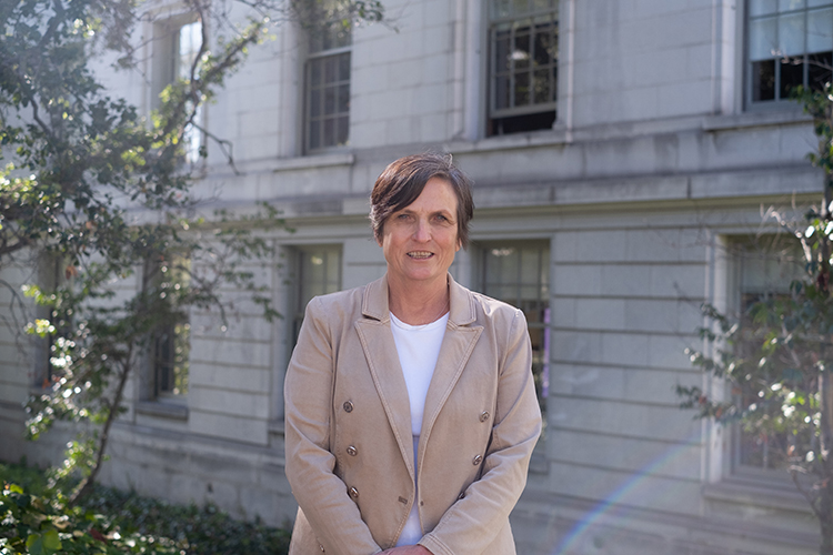 Diane Coppini, director of engineering technical sevices at UC Berkeley's Facilities Services, poses for a portrait outdoors on campus. She has on a beige blazer and has a short haircut.