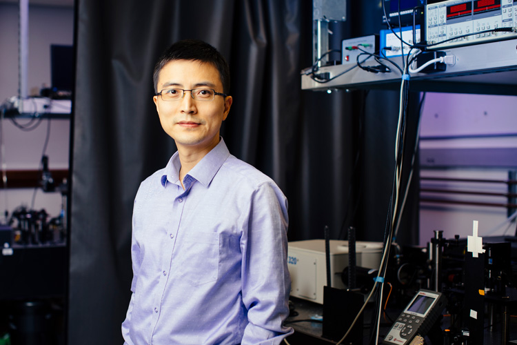 Asian man in blue shirt in darkened lab