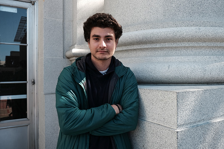 Sarp Kurtoglu, president of the International Students Association, stands against a pillar of Sproul Hall with his arms crossed.