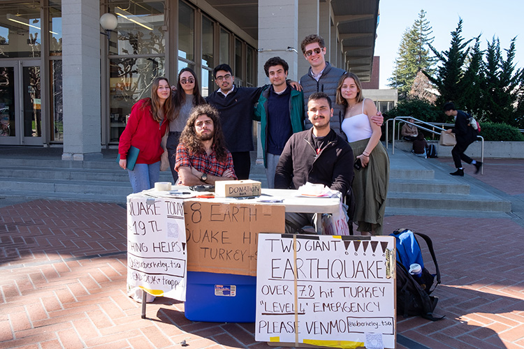 Members of the Turkish Student Association sit and stand at a table on Sproul Plaza where they are collecting quake relief funds.tudents