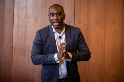 a person stands speaking with hands together