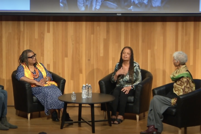 three people sitting and talking on stage