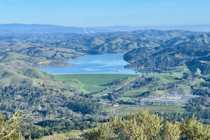A photo shows a hilly green landscape with a lake in the center