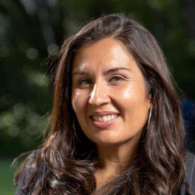 a woman with long, dark hair looking at the camera