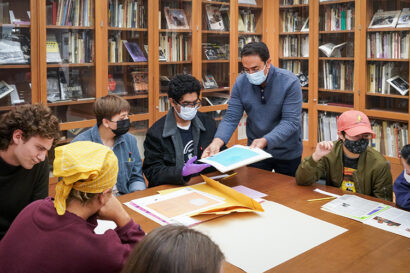 a librarian shows students an artwork