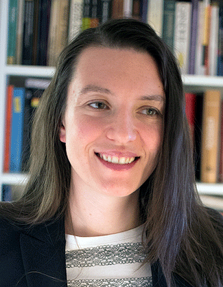 informal headshot of Alia Braley, Ph.D. student in political science, with a wall of books behind her.
