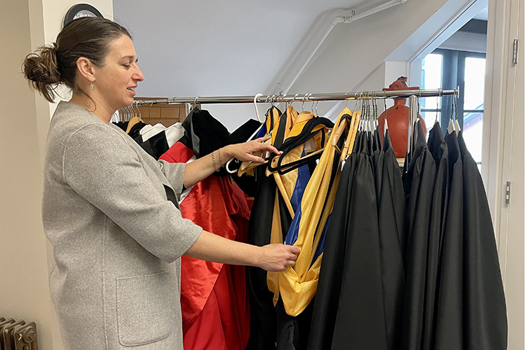 A woman looks through regalia donated by former graduates of the Energy and Resources Group to help students find the right robe and robe length for ceremonies this spring.