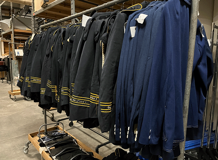 A photo shows a rack of old blue Cal Band uniforms, which resemble military uniforms.