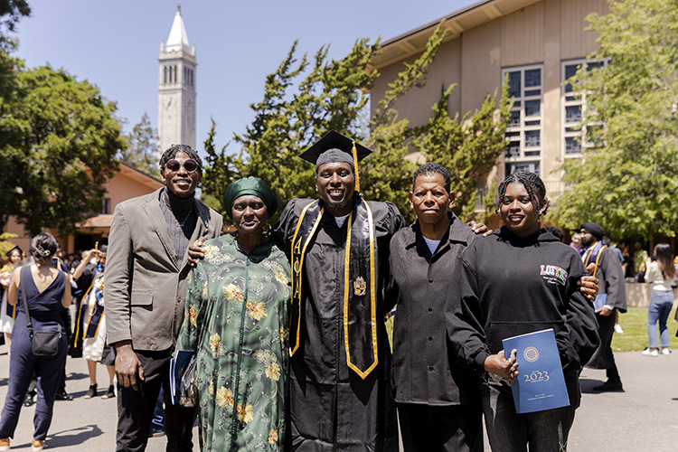 A graduate poses with his family outside of the stadium.