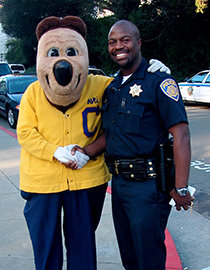person wearing police uniform shaking hand of Oski the Bear