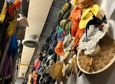 A photo shows a rack of hanging hats that extend from eye level up to a high ceiling.