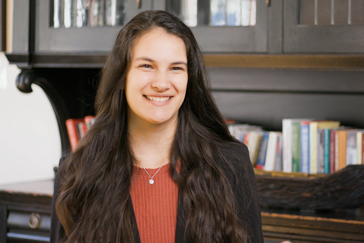 Catey Vera sitting in front of row of books on a desk