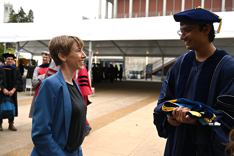 a person talks to a graduate in a cap and gown