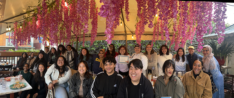 Students posing under a cherry blossom tree.