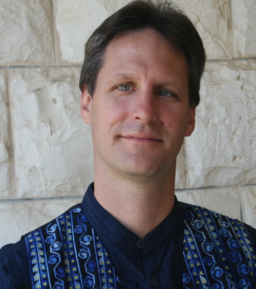 headshot of a person wearing a colorful blue shirt