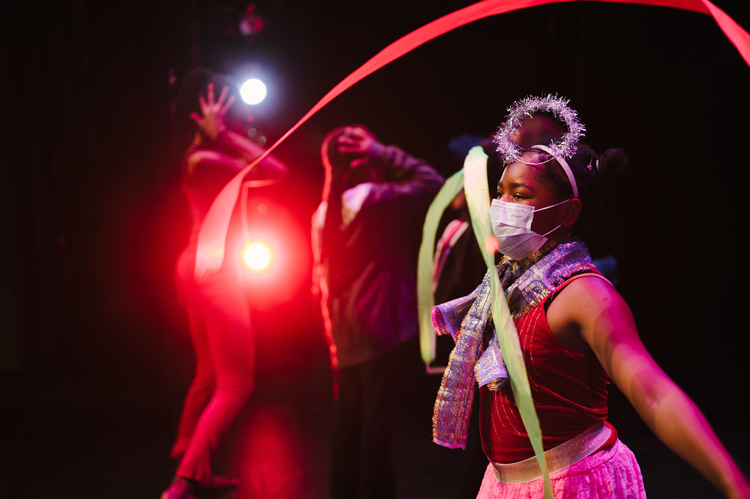 two young dancers perform a fashion show on a dark stage with a red light shining