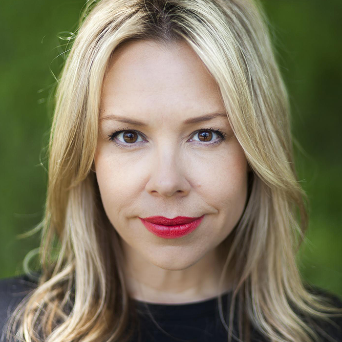 headshot of a person with long blond hair and red lipstick with a slight smile