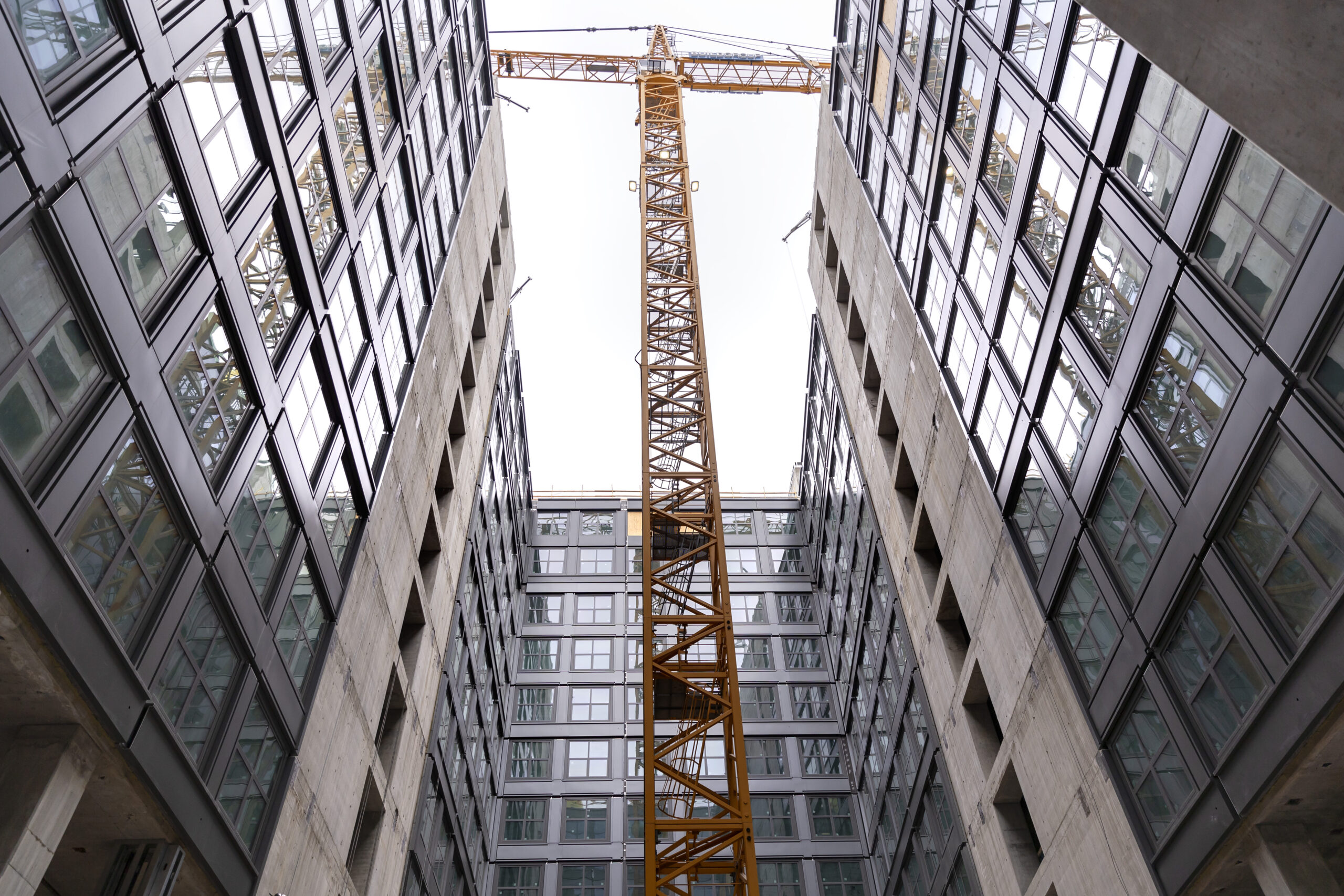 A photo shows a large crane inside the courtyard of a building under construction