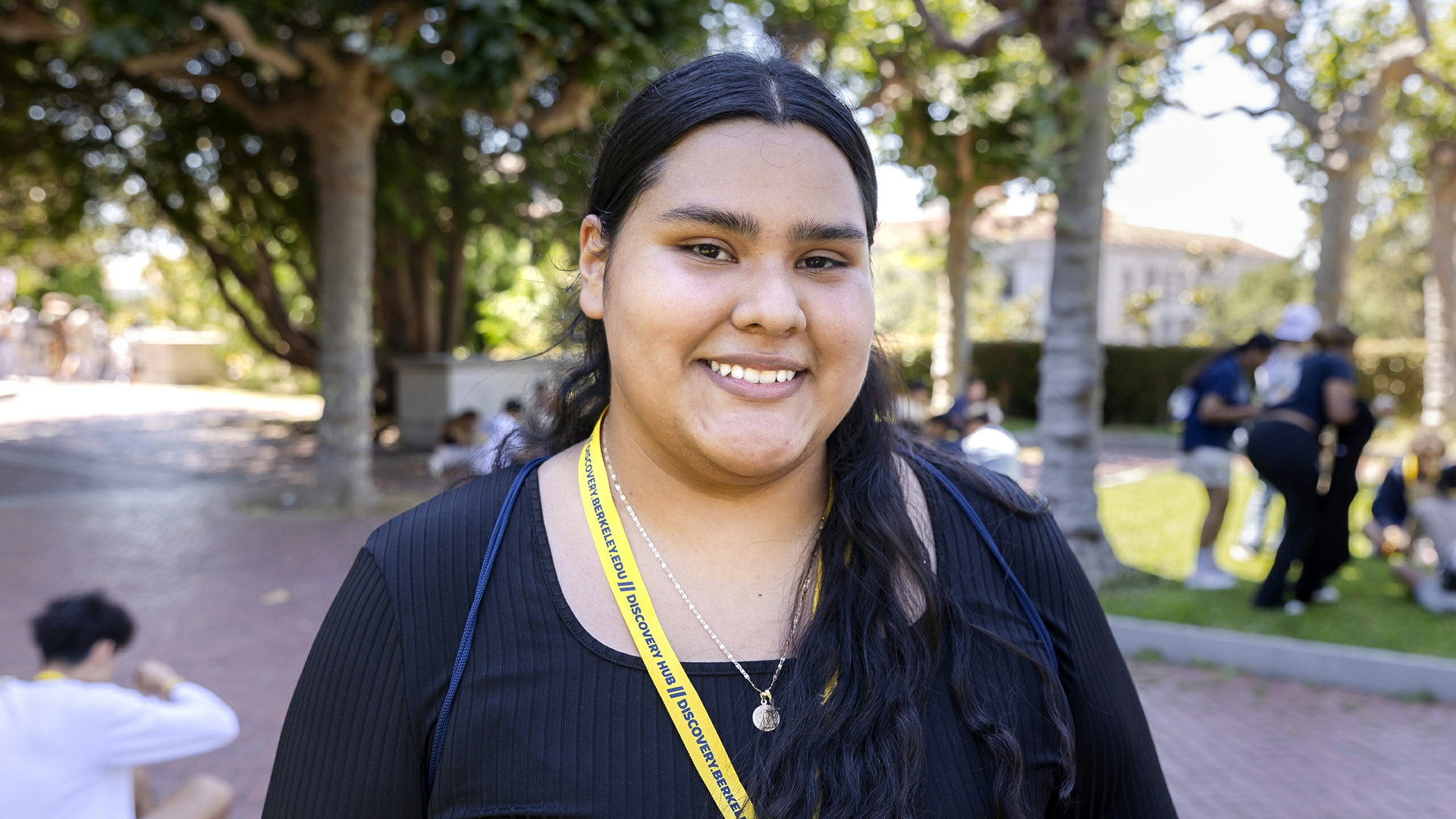 portrait of a Berkeley student smiling and standing outside with trees and other students in the background