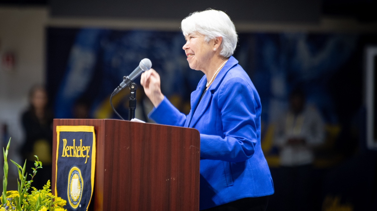 A woman in a blue jacket speaks into a microphone