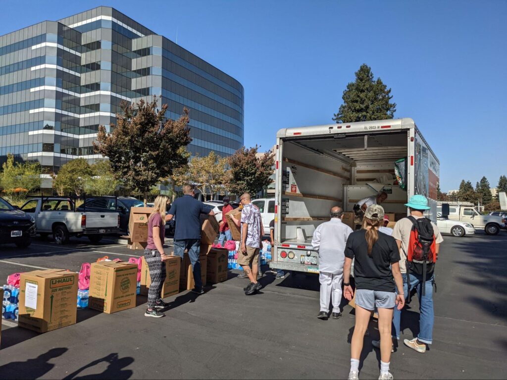 People unload boxes from a box truck in a parking lot