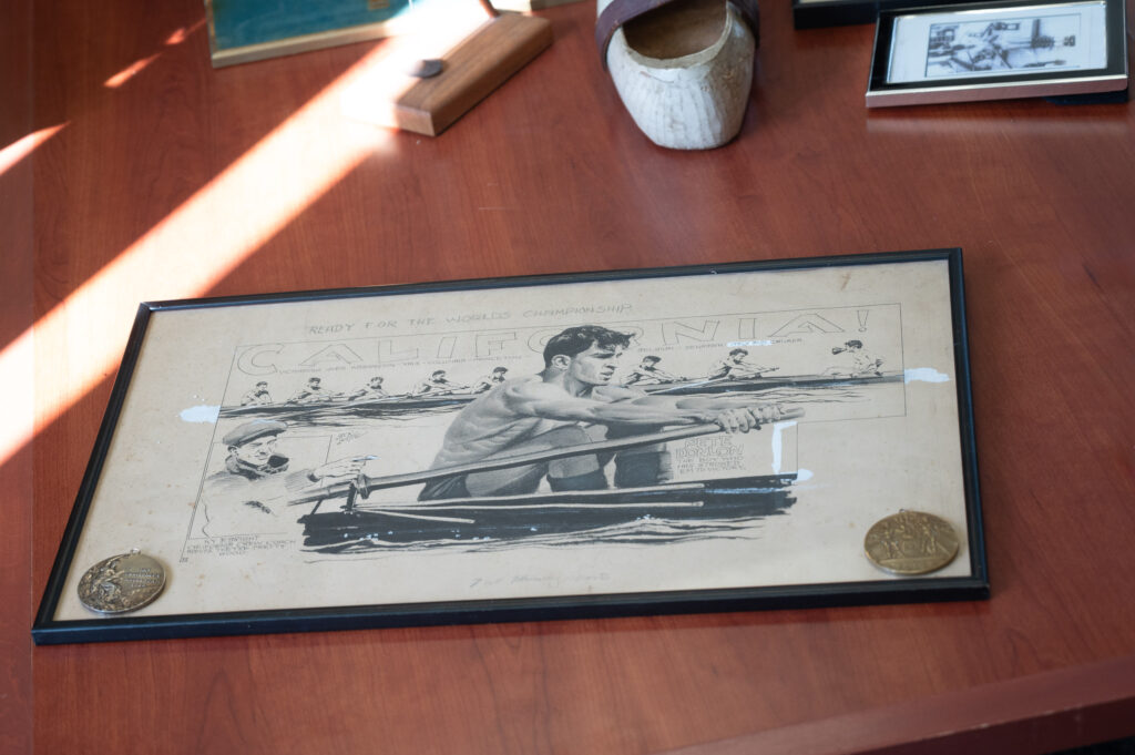 an image of a frame picture on a table of a man rowing; on the framed image are two medals from the 1928 Olympic Games