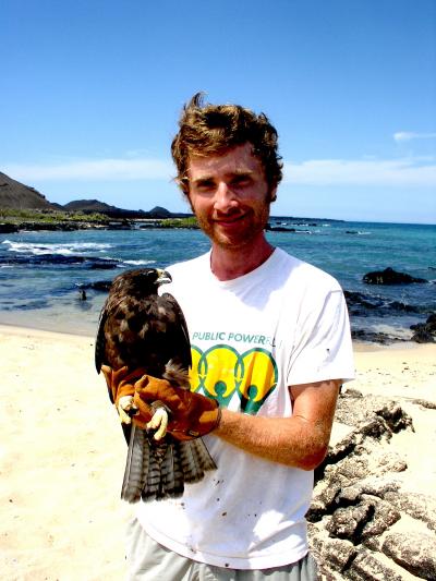 young man on beach holding large hawk