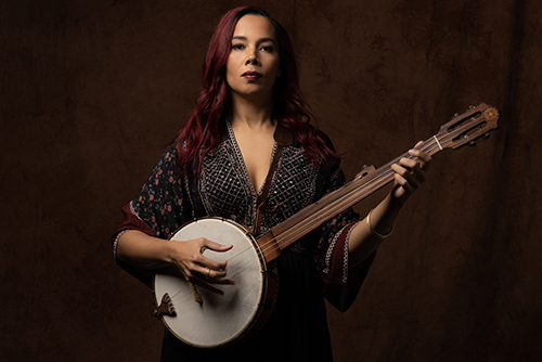Rhiannon Giddens holds a banjo and looks straight ahead