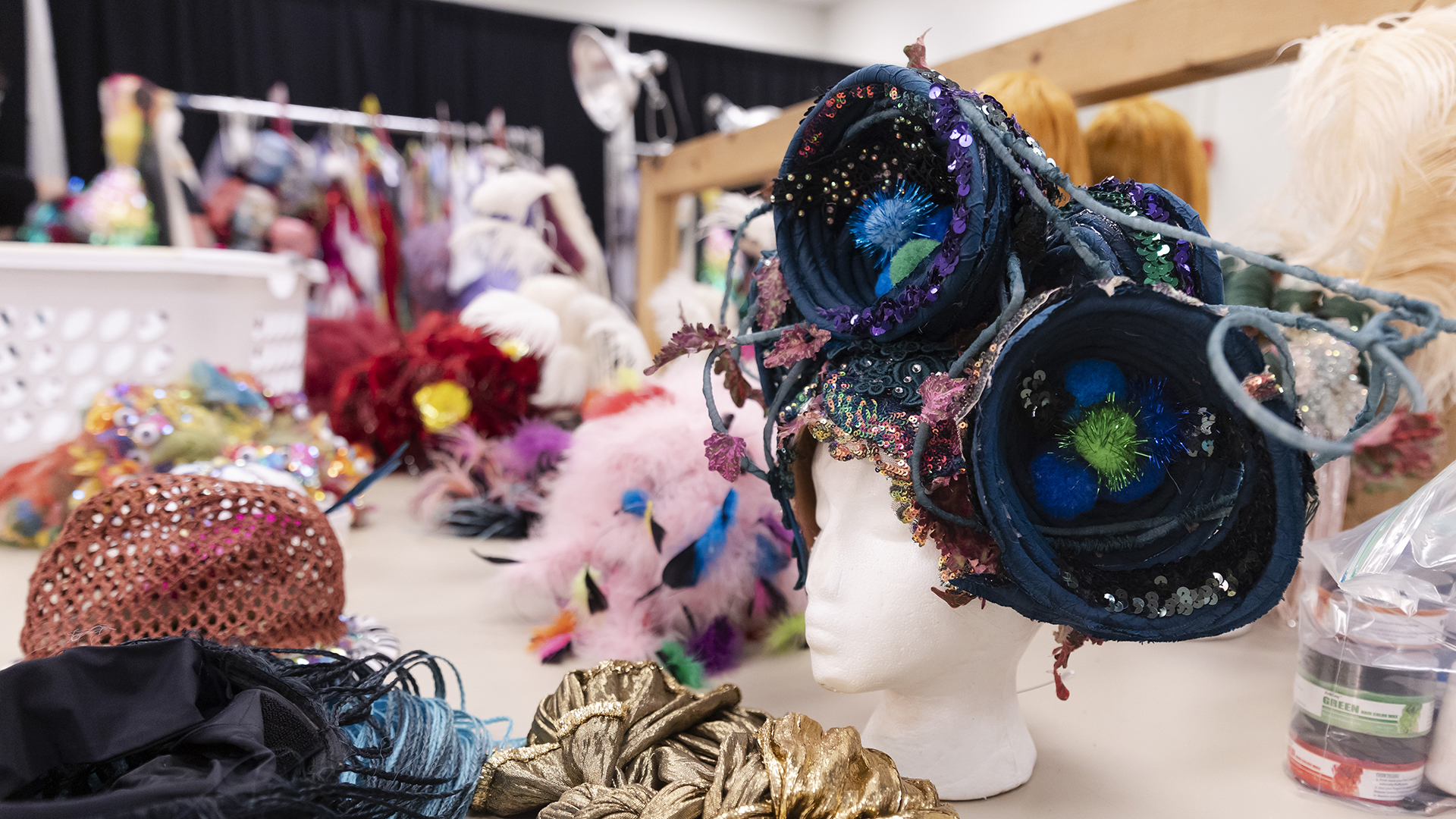 A table of costumes and other materials, including a wig made of two giant blue-green circles in the basic shape of birds' nests, made by Machine Dazzle