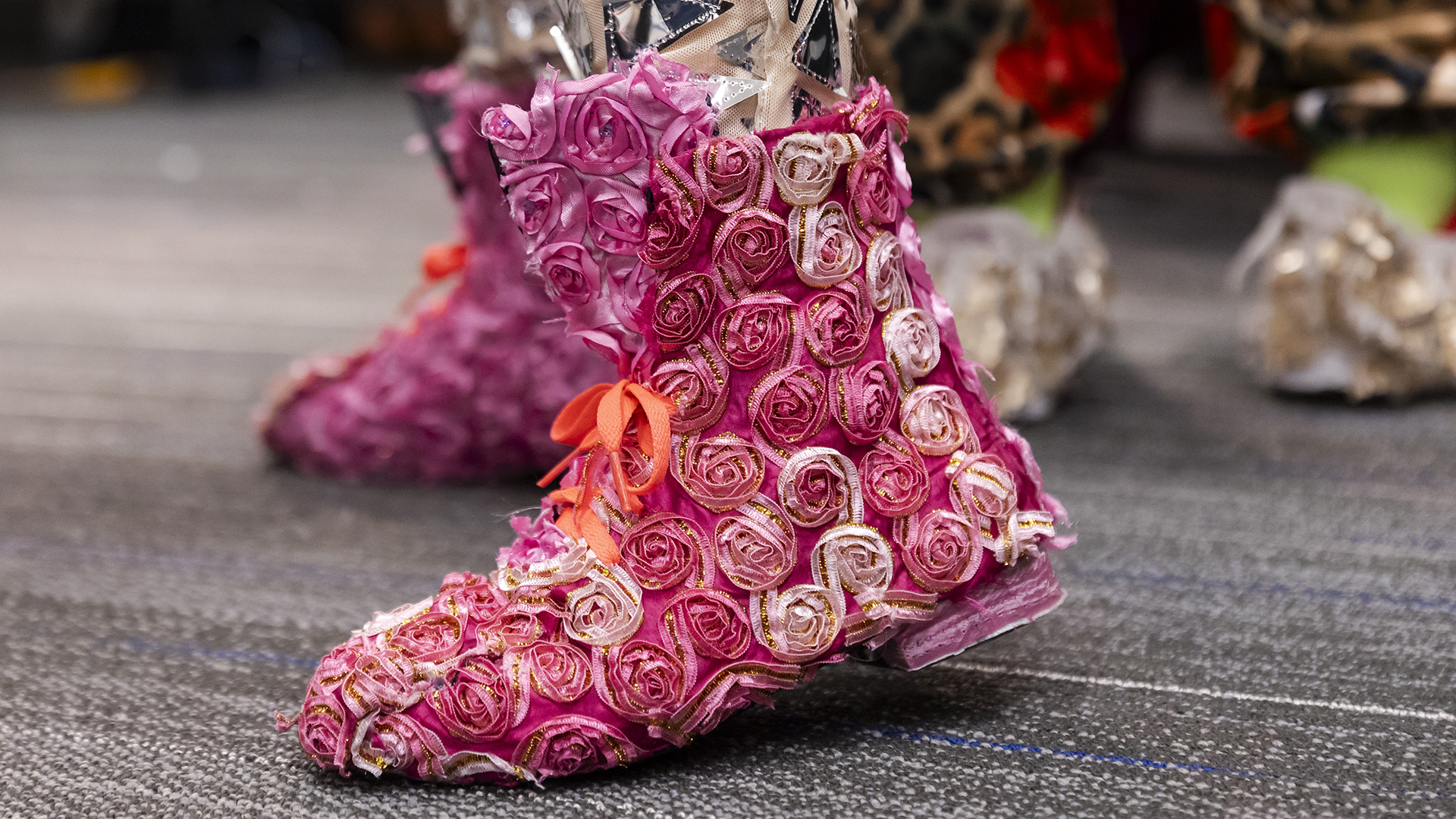 A closeup of a person's feet wearing low-top boots completely covered in pink and white fabric in the shape of little roses
