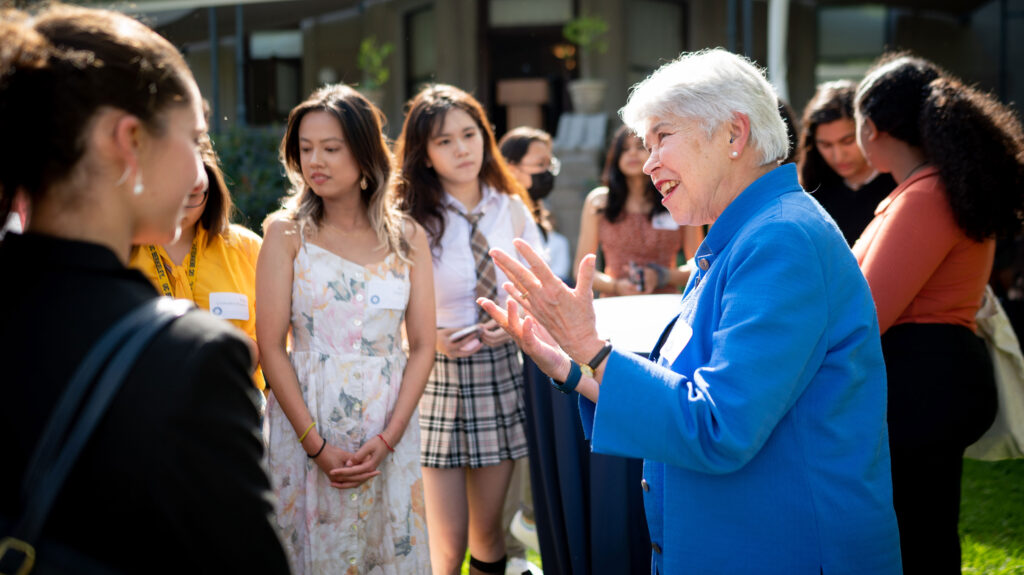 Berkeley Chancellor Carol Christ smiles and gestures as she talks with a group of students.