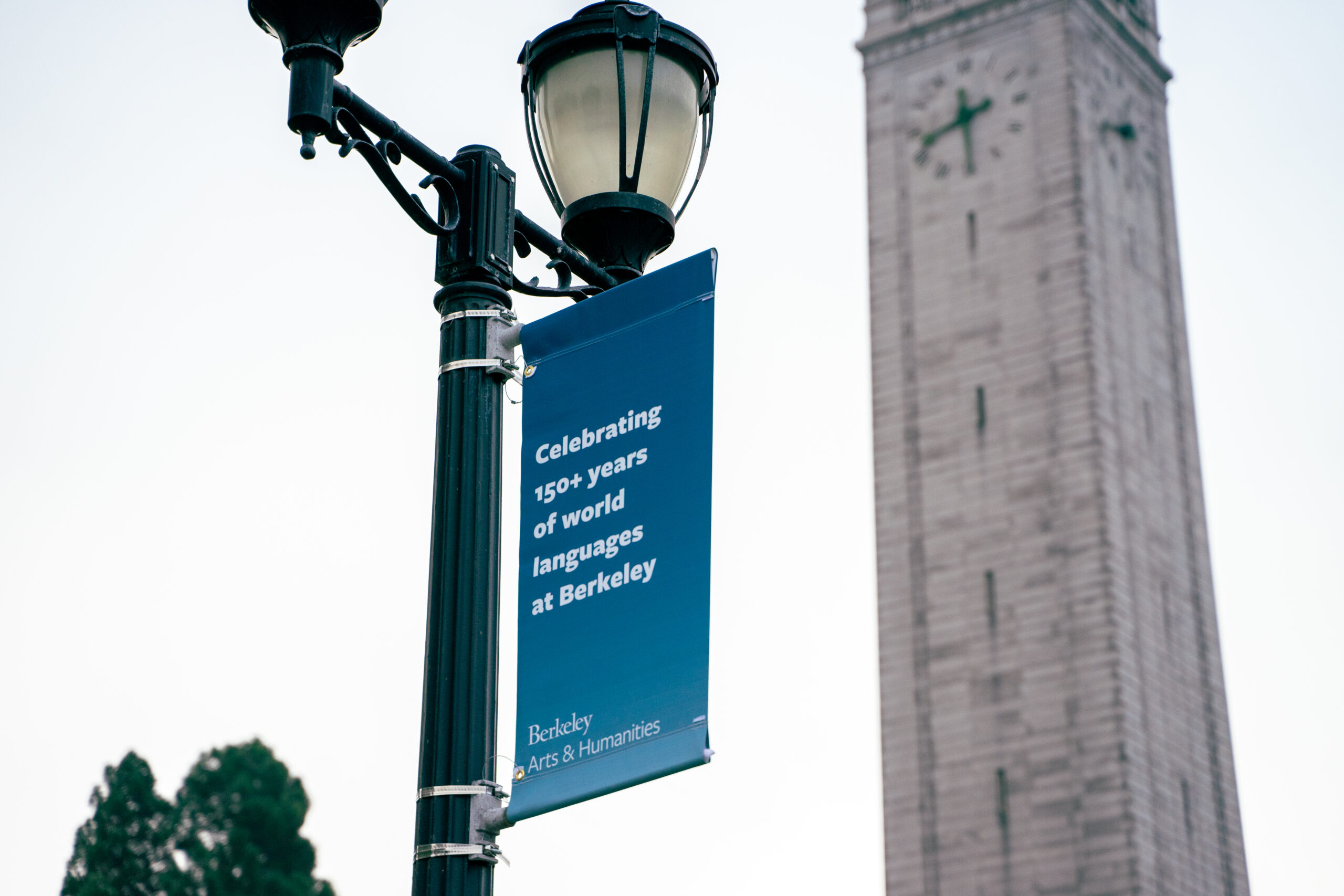 A dark blue banner hanging on a light pole near the Campanile says 