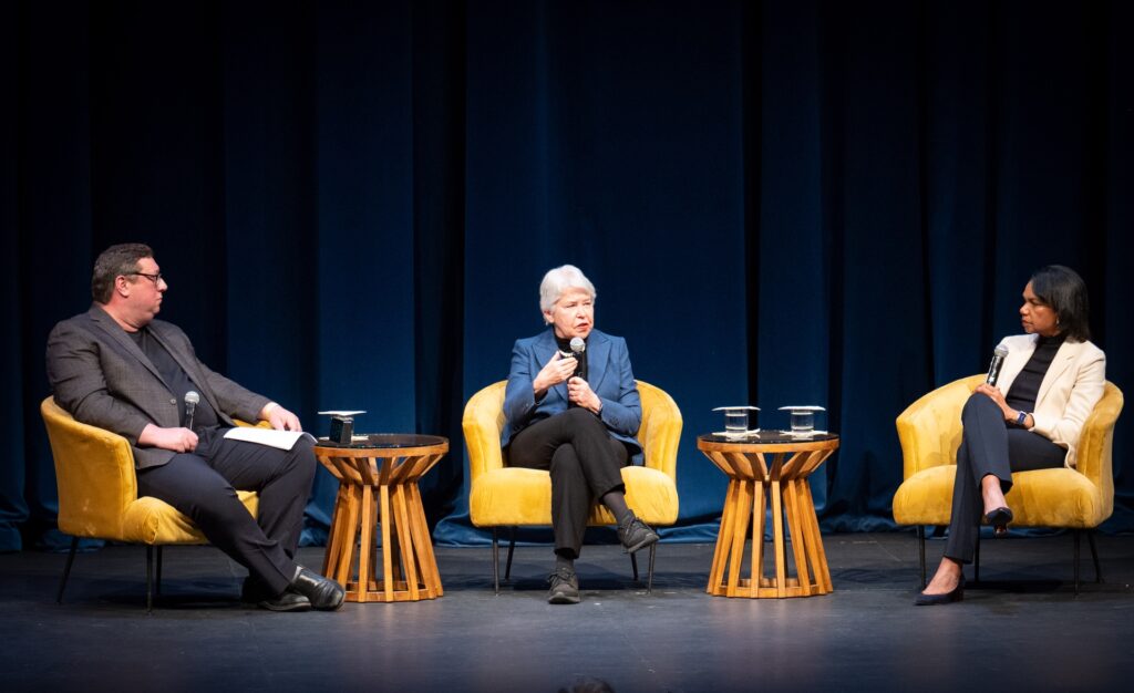 Three people seated on a stage holding microphones and speaking to an audience about the importance and challenges of protecting free speech.