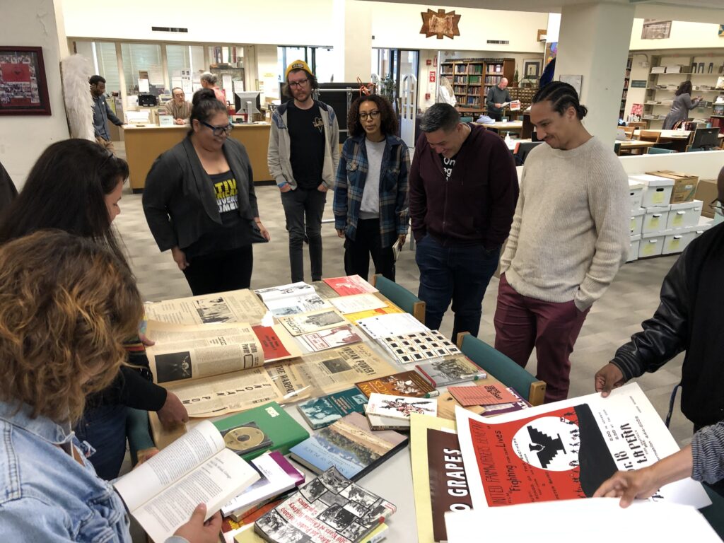 Teachers stand around a table full o historical f newspaper clippings, photographs and flyers.