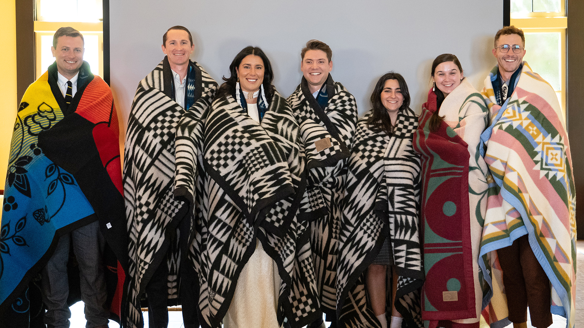 Seven Native law students stand with their new Native blankets they received at their graduation ceremony