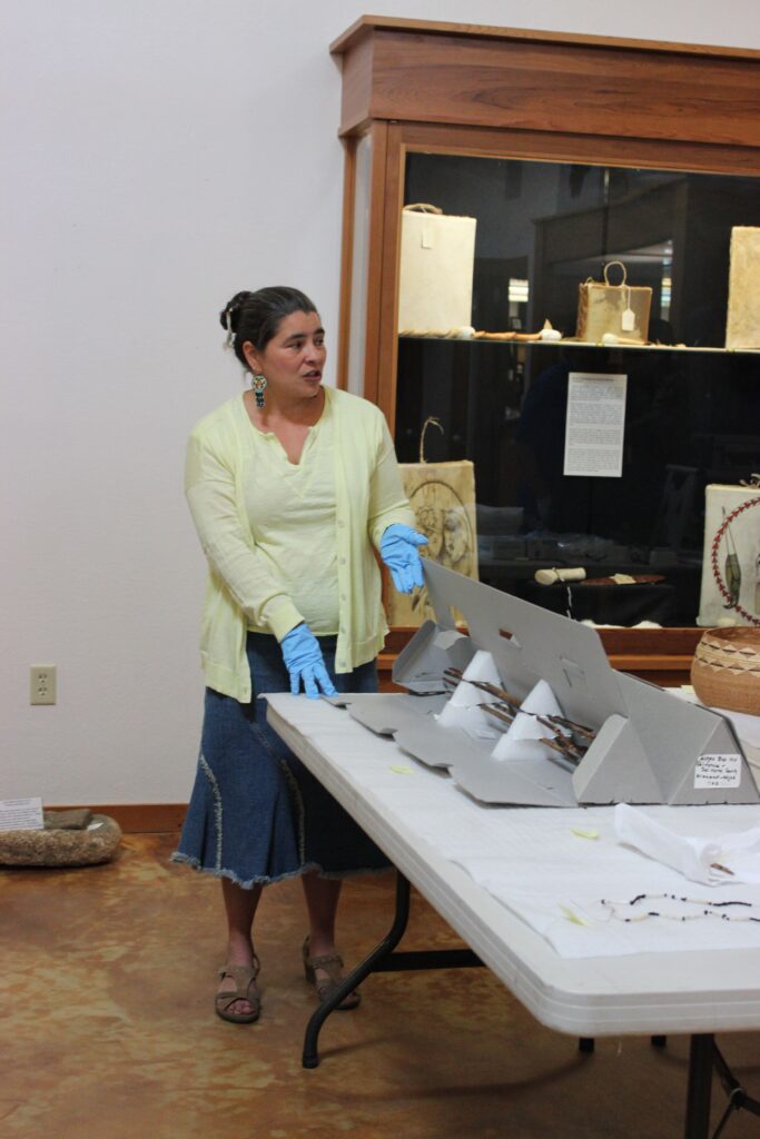 Carolyn Smith wearing a yellow shirt and blue gloves stands near a table